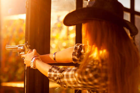Young woman cowboy shooting. Focus on gun.の写真素材