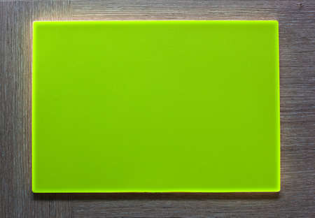 New green plastic plate with empty textspace on wooden background.の写真素材