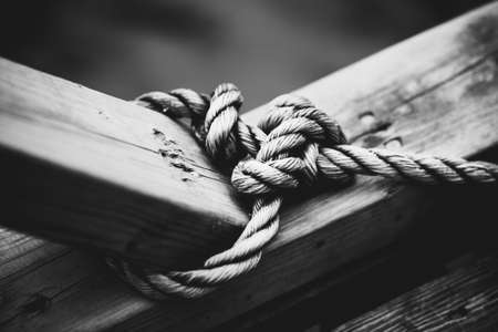 Rope with node on wooden beam. Black and white film style colors.の写真素材