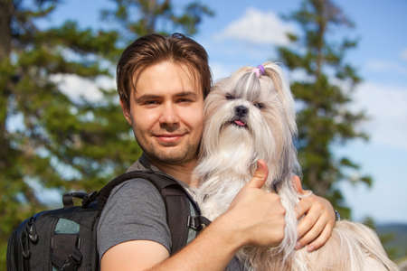 Young smiling man tourist with shih-tzu dog portrait. Showing thumbs up handsign.の写真素材