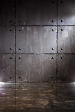 Gray concrete wall with big blocks and floor with reflectionの写真素材