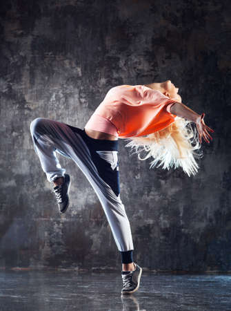 Young woman modern dancer. On stone wall background.