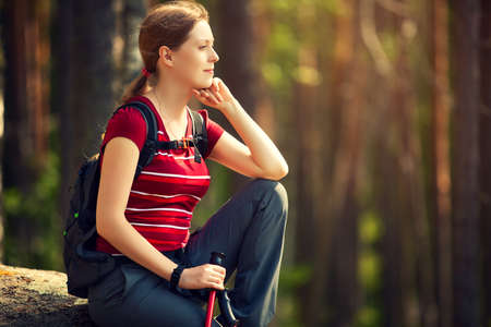 Young woman tourist sitting on stone and looking aside at sunset light.の写真素材