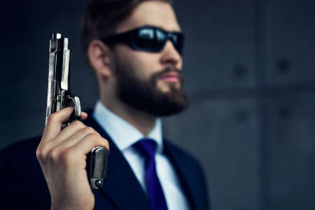 Danger man agent with gun and sunglasses. Focus on gun.の写真素材