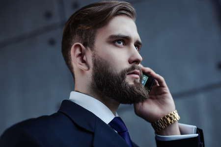 Young handsome businessman with beard talking on phone portrait.の写真素材