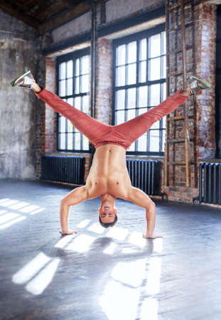 Young man break dancing in old sunny urban interior