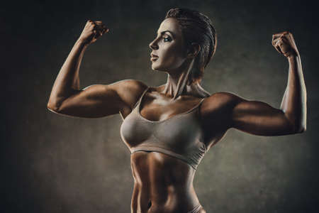 Strong sports woman on wall background. Film style colors effect.