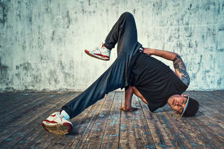 Young man break dancing on wall background. Tattoo on body.の写真素材