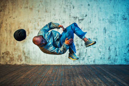 Young man break dancing on wall background. Flip in the air.の写真素材