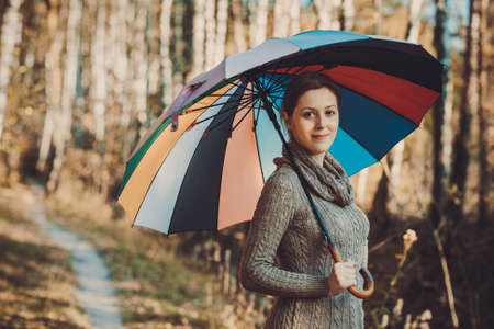Young woman autumn portrait with umbrella. Vintage film style colors.の写真素材