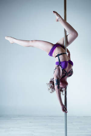 Young sexy pole dance woman on wall background. Tattoo on body.の写真素材