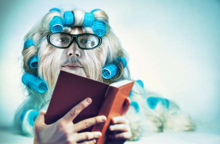 Clever long hair dog with mans face in glasses reading book. Mutation and genetic modification  fun concept.の写真素材