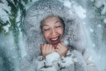 Young woman with falling snow winter emotional fun portraitの写真素材