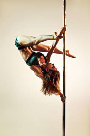 Young slim sexy strong pole dance woman upside down. Warm colors.の写真素材