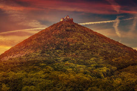 Castle on high mountains top with forest at sunset red colorsの写真素材