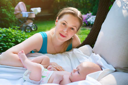 Mother with three month baby outdoors sunny portrait in gardenの写真素材