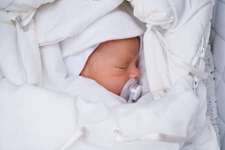Three month baby in white clothing sleeping outdoorsの写真素材