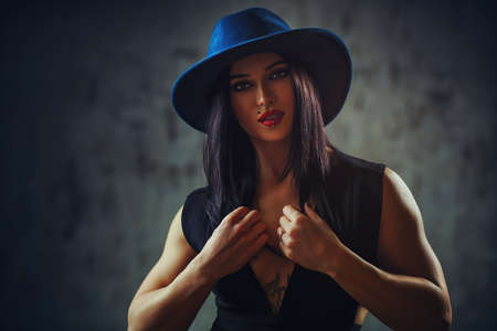 Young elegant brunette woman in hat portrait. With tattoo on body and piercings on face.