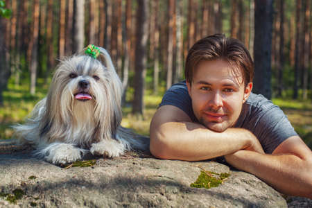 Young man with shih tzu dog portrait in forestの写真素材