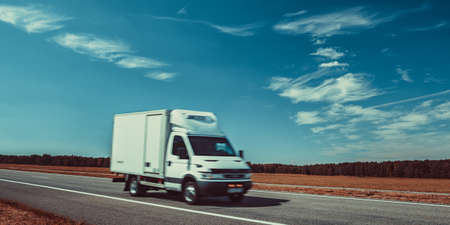 Light truck travel on europe road. Blue sky and autumn field panorama.の写真素材