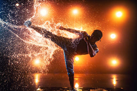 Young man break dancer making kick on splashing water. Tattoo on body.の写真素材