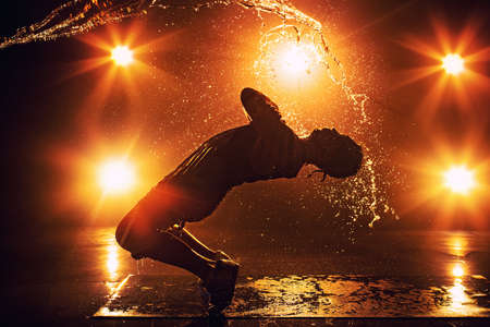 Young man break dancer with lights and water effects. Tattoo on hand.