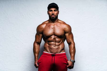Young strong man bodybuilder in cap on bright white backgroundの写真素材