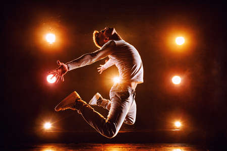 Young man break dancer jumping high in club stage with lightsの写真素材