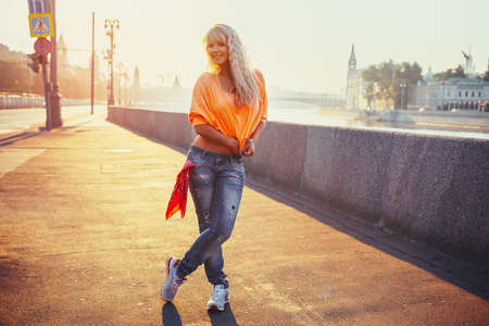 Young cool teenage style woman standing on stone quay at morning sunriseの写真素材
