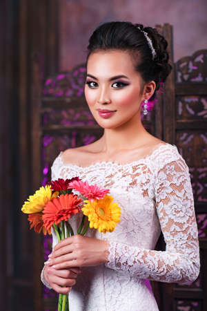 Young asian woman with flowers portrait on wall backgroundの写真素材