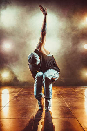 Young cool man break dancing in club with lights and smoke. Tattoo on body.の写真素材