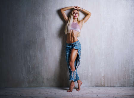 Young slim sexy blond woman fashion portrait on gray wall backgroundの写真素材