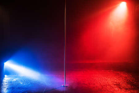 Studio stage with pole for dancing in center. Blue and red lights. Water effect.の写真素材