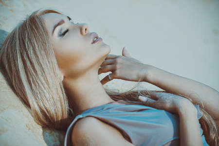 Young blond woman outdoors tender portrait on sandの写真素材