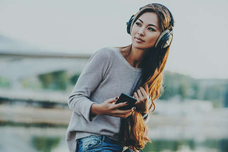 Young asian woman with headphones portrait on city background