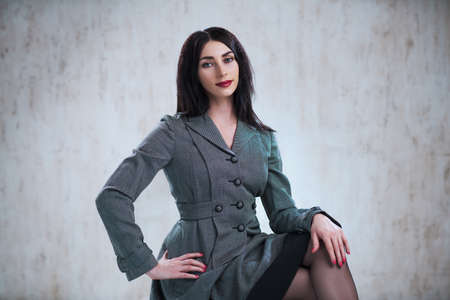 Young sitting business woman portrait on gray wall background