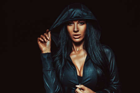 Young sexy brunette woman in hood dark night portraitの写真素材