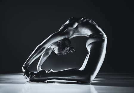 Young topless woman stretching. Silver body paint and toning for metallic skin effect. Dramatic colors.の写真素材