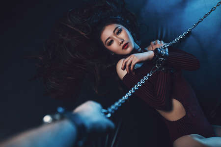 Young asian woman with chain sexy bdsm style portrait. Male hand holding chain.の写真素材