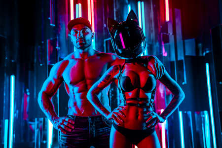 Strong man and woman posing in neon blue and red club lights. Tattoo on body.の写真素材