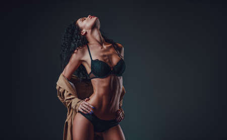 Young slim woman posing in black lingerie and cloakの写真素材