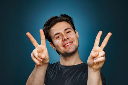 Young brunette man positive peace sign portrait
