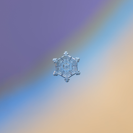 Snowflake glittering on blue gradient background. Macro photo of real snow crystal: small sectored plate with glossy surface, relief centrel hexagon, six broad arms and complex inner pattern.の写真素材