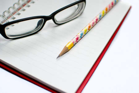 Closeup of reading glasses and pen  on the book isolated on white backgroundの写真素材