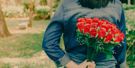 Vintage style photo of woman is hiding flowers behind their back.の写真素材