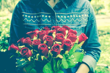 Vintage style photo of woman is hiding flowers behind their back.の写真素材