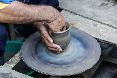 hands of a man, creating an earthen jar on the circle