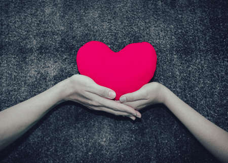 Young man giving a heart-shaped pillow his sweetheart on Valentine's Day. Love beautiful conceptの写真素材