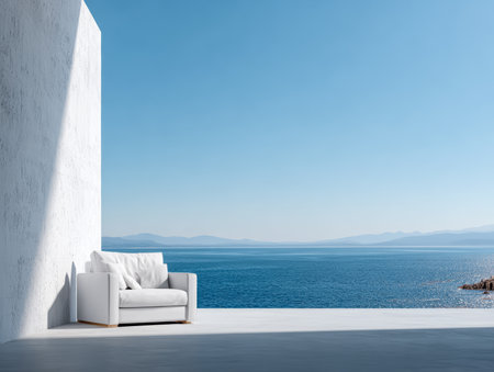 A modern white sofa sits alone on a minimalist terrace overlooking the calm ocean. The clear blue sky and distant mountains enhance the peaceful atmosphere of the scene.の素材