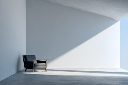 A modern black armchair rests against a bare wall, paired with a small side table. Soft natural light streams in, highlighting the minimalist design and spacious feel of the room.の素材